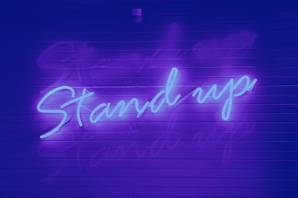 a neon sign on a wall that says stand up