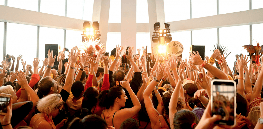 A photo of a crowd of people with their hands in the air at an LG Experience Happiness event