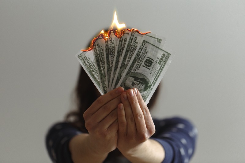 a woman holding burning money