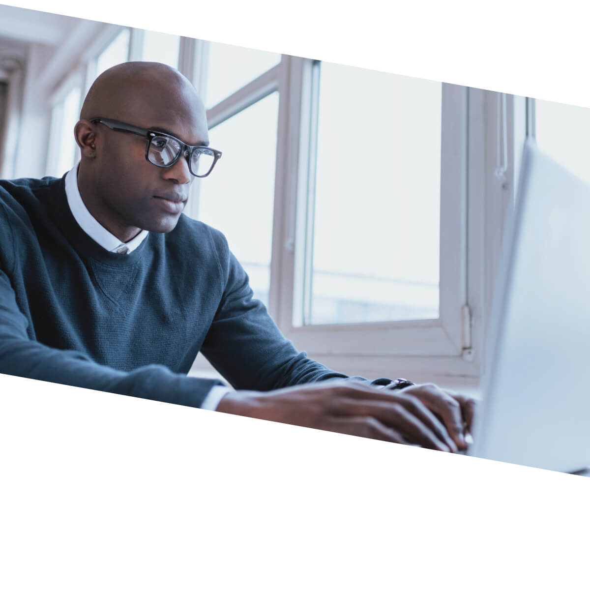 African American man with glasses typing on a laptop